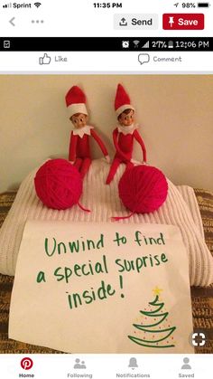 two elfs sitting on top of a bed next to a sign that says, unwind to find a special surprise inside