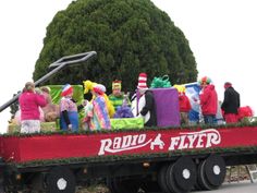 people in costumes are riding on the back of a truck with presents and stuffed animals