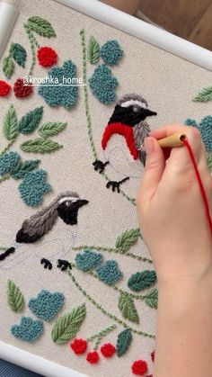 a child is working on an embroidered piece with birds and berries in the background, while holding a crochet hook