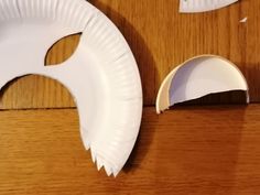 a white paper plate with a hole in it next to a piece of paper on a wooden surface