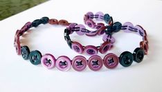 three bracelets with different colored buttons on them