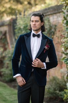 a man in a tuxedo and bow tie is posing for the camera with his hands in his pockets