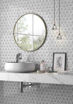 a white sink sitting under a round mirror in a bathroom next to a wall mounted faucet