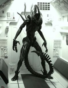 a black and white photo of an alien standing in a space station with the door open