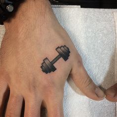 a man's hand with a dumbble weight tattoo on it