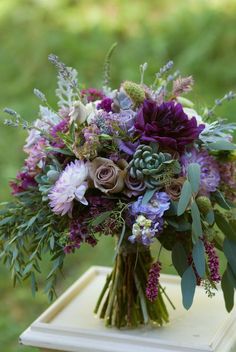 a bouquet of flowers sitting on top of a wooden table in front of green grass