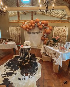 a room filled with tables and chairs covered in white tablecloths next to a cow print rug