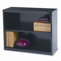 a black bookcase with two books and a purple bowl on it's shelf