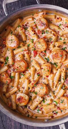 a pan filled with pasta covered in cheese and tomato sauce on top of a wooden table