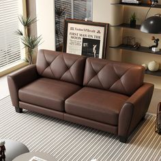 a brown leather couch sitting in a living room next to a book shelf filled with books