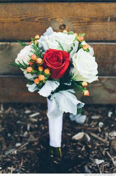 a bridal bouquet with red and white flowers on the ground next to a wooden box