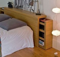 a bed sitting next to a night stand on top of a wooden floor