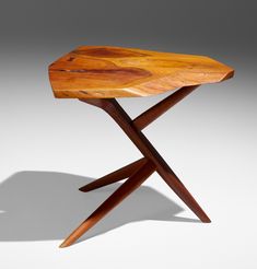 a wooden table with two crossed legs and a wood slab on the top that is shaped like an x