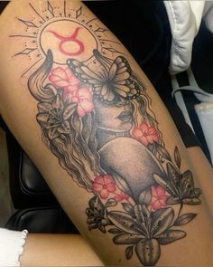 a woman's thigh with flowers and an astro sign on the side, in black and grey