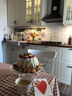 a cake sitting on top of a table next to a cup of coffee in a kitchen