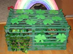 a wooden box with green shamrocks on it and a rainbow in the background,