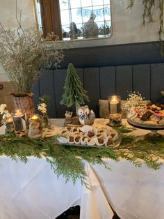 a table topped with lots of food next to candles and trees on top of it