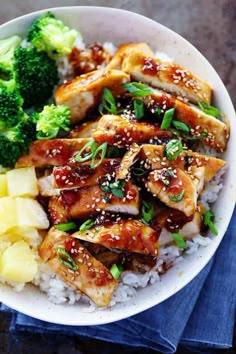 a white bowl filled with rice, chicken and broccoli on top of a blue napkin