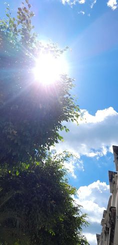 the sun shines brightly in front of some buildings on a sunny day with blue skies and white clouds