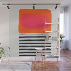 an orange and pink painting on the wall in a room with wooden flooring, white walls