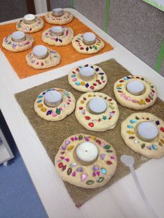 decorated cookies sitting on top of a table next to a lit tealight candle and napkins