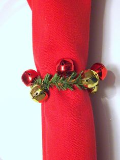 a red napkin with bells and greenery on the edge is sitting on a white plate