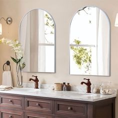 two oval mirrors are above the double sinks in this bathroom