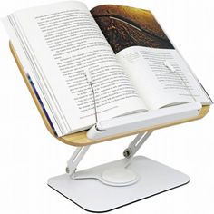 an open book sitting on top of a wooden table with a white base and metal feet