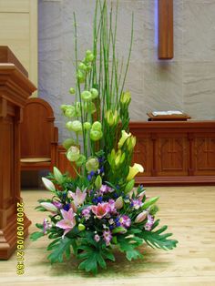 a large arrangement of flowers on the floor in front of a church alter with pews