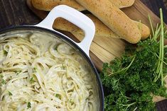 pasta and bread on a cutting board next to a pot with broccoli in it