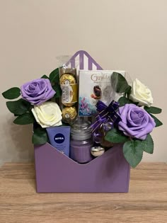 a purple gift box filled with chocolates, flowers and other items on top of a wooden table