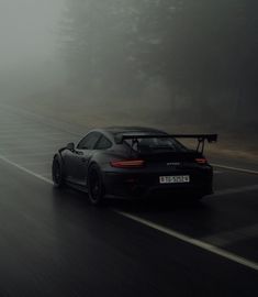 a black sports car driving down a foggy road