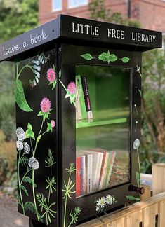 a little free library with books and flowers painted on it