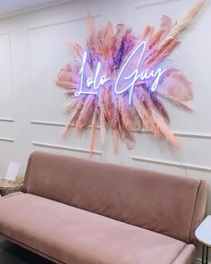 a pink couch sitting in front of a neon sign