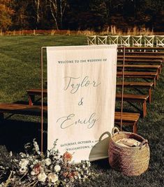 a welcome sign sitting on top of a grass covered field next to a wooden bench