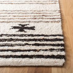 an area rug with black and white stripes on the floor, in front of a wooden floor