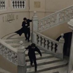 three people are walking up the stairs in an old building with white railings and wrought iron balconies