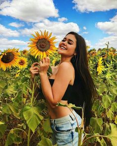 a beautiful young woman standing in a sunflower field