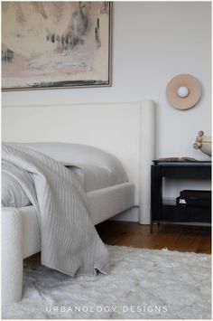 a white bed sitting in a bedroom next to a painting