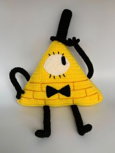 a crocheted yellow triangle with a black bow tie on it's head