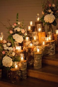 there are many candles on the steps with flowers in vases next to each other