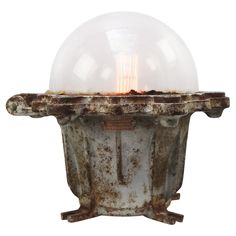 an old light fixture with a glass ball on it's top and rusted metal base