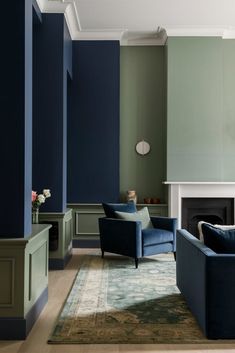 a living room with two blue chairs and a rug on the floor in front of a fireplace