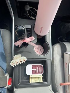 the interior of a car with various items in it and a pink cup on top