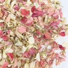 a pile of pink and white flowers on top of a white tablecloth covered in dirt