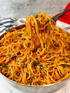 a spoon full of spaghetti being lifted from a pan