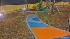 an empty playground at night with lights shining on the ground and children's play area in the background