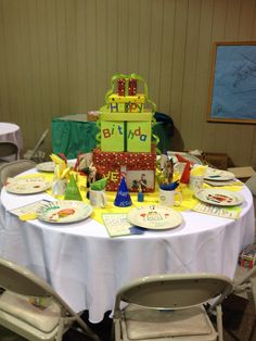 a birthday cake sitting on top of a table with plates and napkins around it