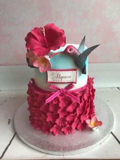 a cake decorated with pink flowers and a humming bird