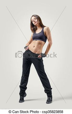 a beautiful woman in black pants and sports bra top posing with her hands on her hips